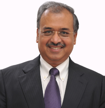 Studio portrait of Dilip Shanghvi in a dark suit and purple tie against a white background.