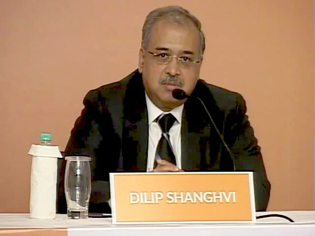 Dilip Shanghvi speaking at a press briefing with a nameplate reading Dilip Shanghvi in front of him.