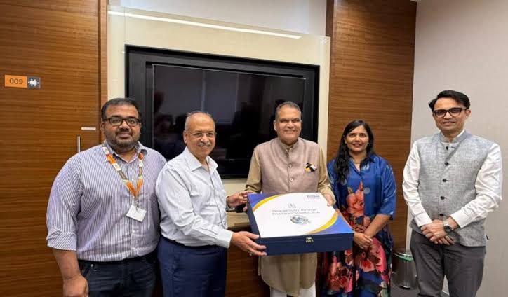 Dilip Shanghvi at an institutional meeting, presenting a commemorative folder with four colleagues.