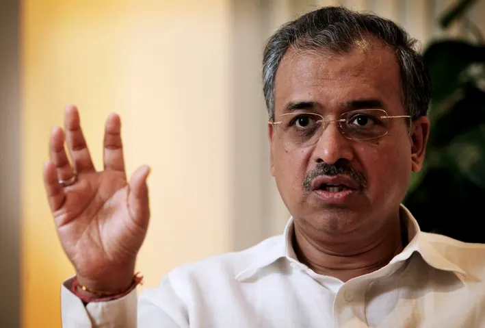 Dilip Shanghvi in a white shirt, gesturing with one hand while speaking during an interview.