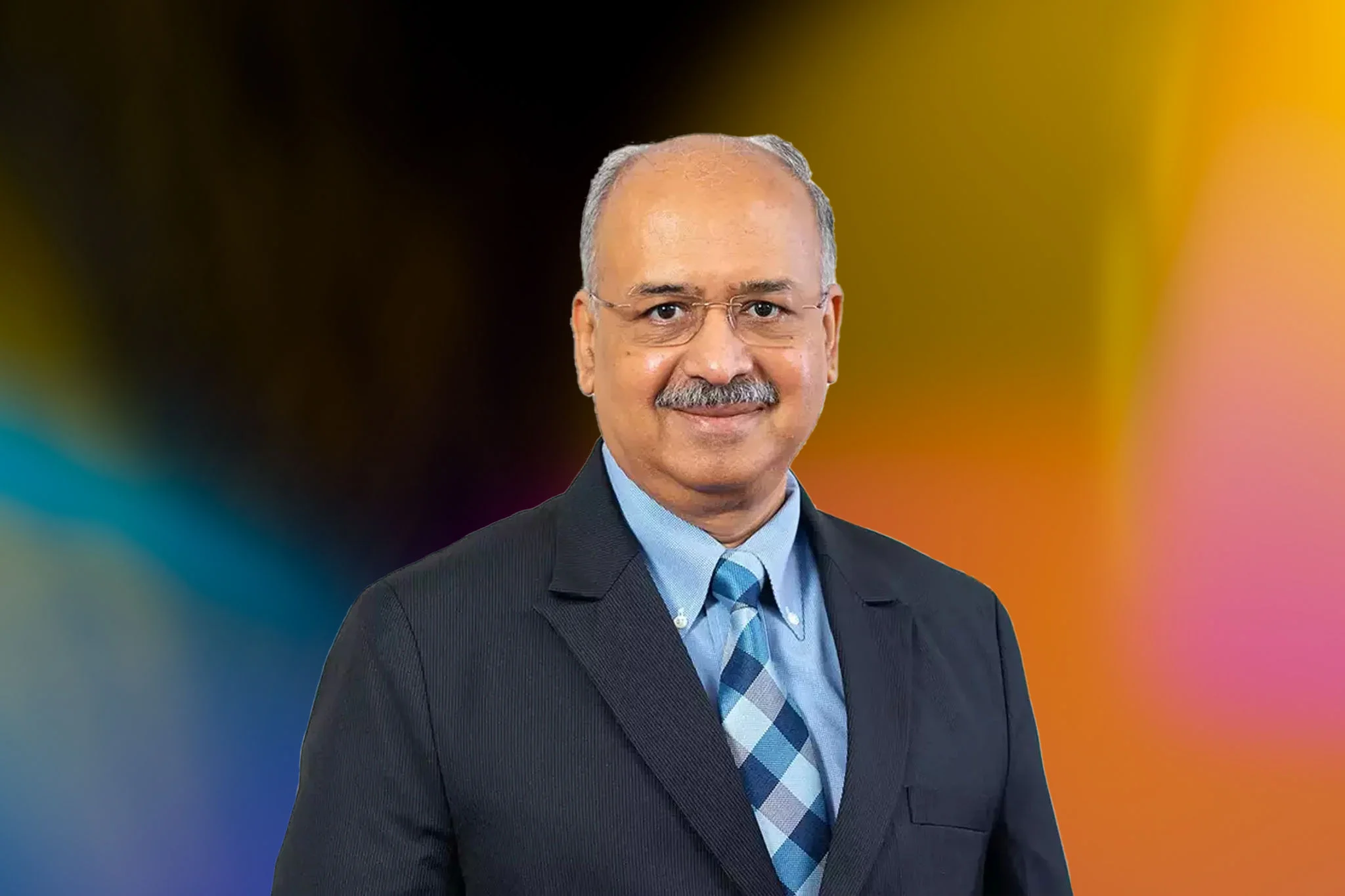 Portrait of Dilip Shanghvi in a dark suit against a background of overlapping coloured light.