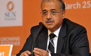 Dilip Shanghvi speaking at a Sun Pharma briefing against an orange branded backdrop.