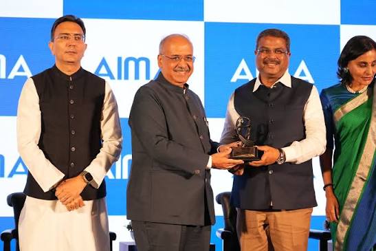 Dilip Shanghvi presenting an award trophy on stage at an All India Management Association event.