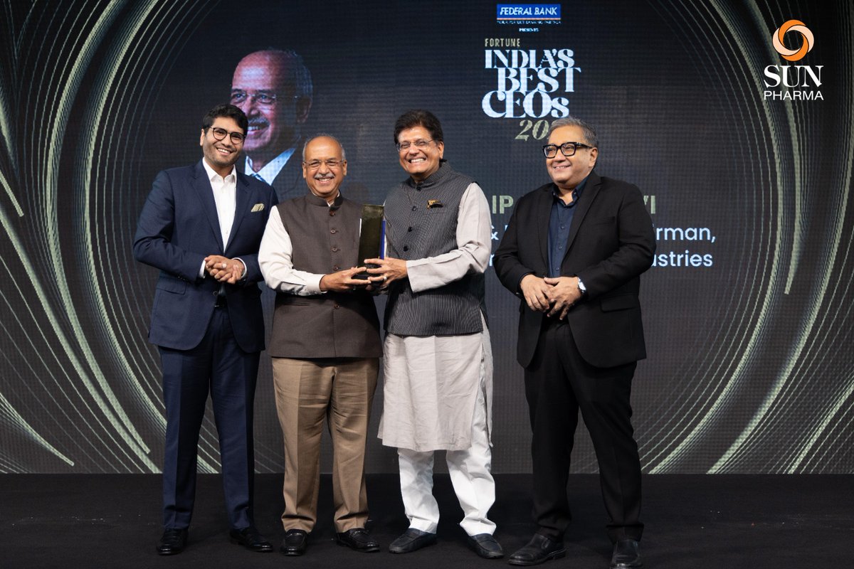 Dilip Shanghvi on stage at the Fortune India Best CEOs ceremony, holding a trophy with three other people.